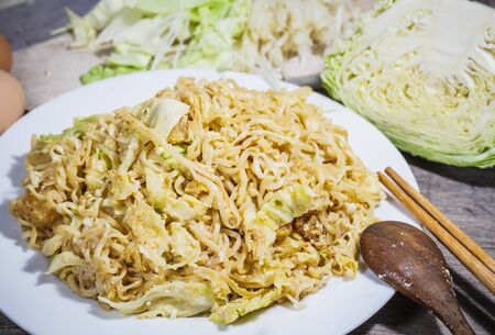 Stir fried noodles with vegetables in brown plate and on wood boardの写真素材