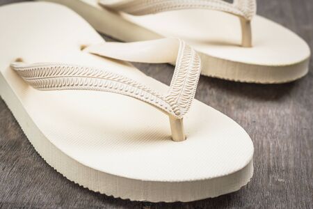 Flip-flops cream color on a wooden background.