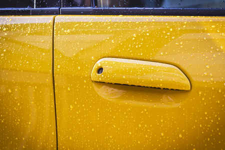 Handle of yellow car door in raining day.の写真素材