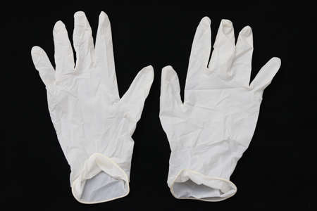 Pair of two medical white rubber gloves on black background. Disposable gloves concept for health care and medical procedures.の写真素材