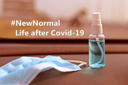 Quote about new normal with medical mask , hand sanitizer spray and Covid-19 (Coronavirus) pandemic. Face Mask with Alcohol based hand sanitizer spray placed on the car console.の写真素材