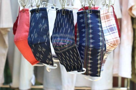 Colorful washable reusable fashion face masks hanging on the clothes hanger. Making DIY cloth masks to prevent the outbreak of the Covid-19 virus has become a popular fashion throughout Thailand.の写真素材