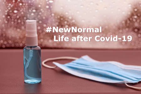 Quote about new normal with medical mask , hand sanitizer spray and Covid-19 (Coronavirus) pandemic. Medical face Mask with alcohol based hand sanitizer spray placed on the car console.の写真素材