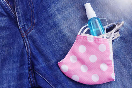 DIY cloth face mask and hand sanitizer spray placed on blue jean background. Concept for the new normal or new lifestyle after COVID-19 Coronavirus pandemic.の写真素材