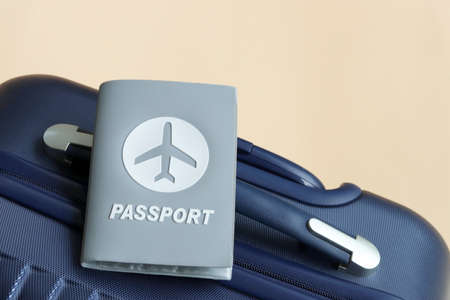 Passport placed on blue suitcase on cream background with copy space. Lifestyle and traveling concept in New Normal after Covid-19 / Coronavirus pandemic.の写真素材