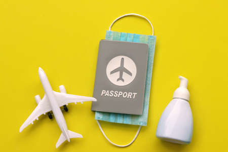 Passport with medical face mask ,hand sanitizer gel and airplane on yellow background with copy...