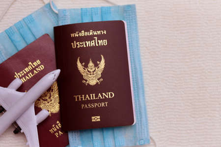 Two Thai Passports with medical face masks and airplane on white background with copy space. Lifestyle and traveling concept in New Normal after Covid-19 / Coronavirus pandemic.の写真素材