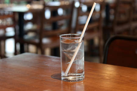 Fresh water in glass with paper drinking straw on restaurant background. Concept for reduce plastic pollution and support green eco friendly products.の写真素材