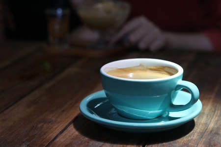 Hot black coffee or Americano in blue ceramic cup on wooden table background.