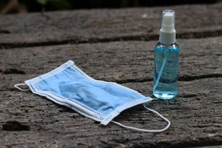 Hand sanitizer spray and
 blurred surgical mask on wooden table. Concept about new normal,social distancing,business, 
 and travel guidelineの写真素材