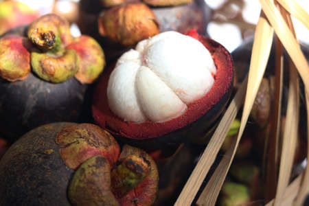 Queen of fruit, Mangosteen in bamboo basket. Cross section of mangosteen showing the deep purple...