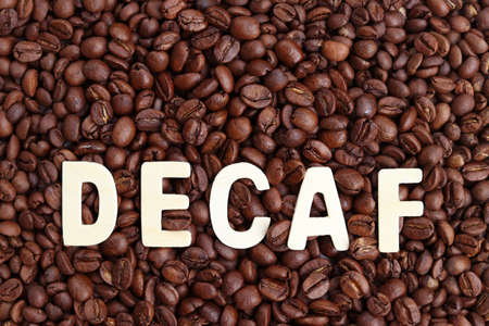 Decaf word on roasted coffee beans background. Concept of decaffeinated coffee or low caffeine coffee.の写真素材