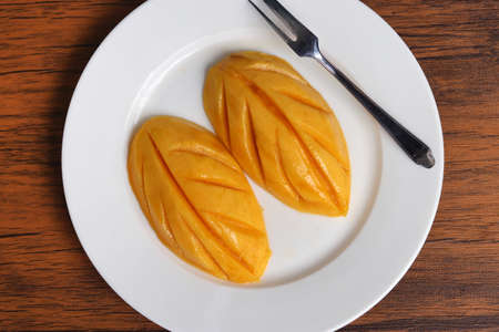 Custard on white plate with spoon on wooden background.