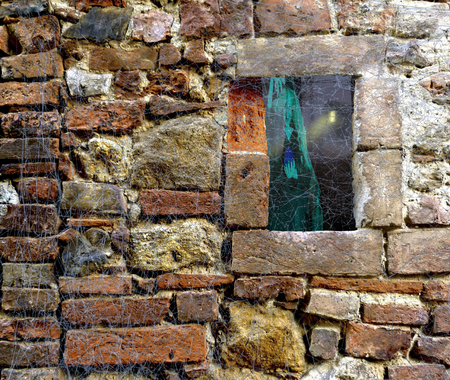 Halloween stone brick wall covered in spider web rags with a window looking on a scary horror forest with cabin and ghost witchの写真素材