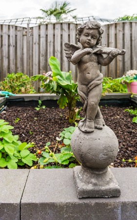 stone sculpture of a little angel holding a violin instrument garden decorationのeditorial素材