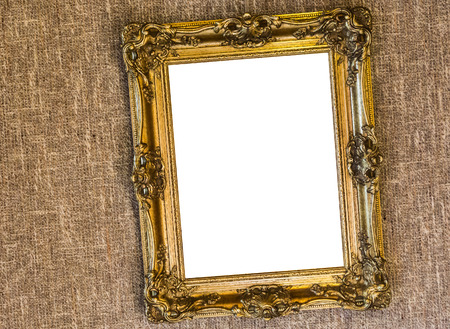 Empty crooked hanging antique expensive looking golden painting frame hanging on a sackcloth wallの写真素材