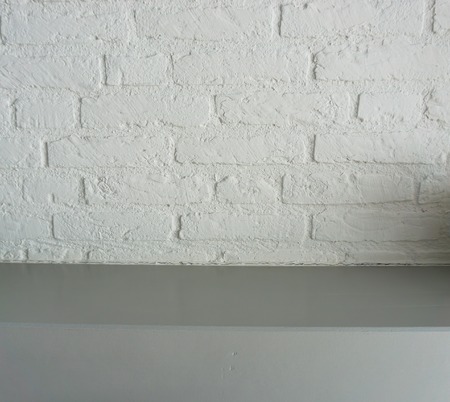 empty surface grey wooden table top with a white brick wall backgroundの写真素材