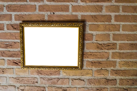 empty golden vintage painting frame hanging on a brick wall backgroundの写真素材