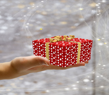 Isolated hand holding a decorated wrapped present and giving it away on a christmas background with starsの写真素材