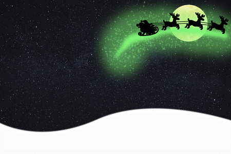 merry christmas card santa claus flying in the air on his sleigh leaving magical sparkle star dust at night time with a sky filled with starsの写真素材