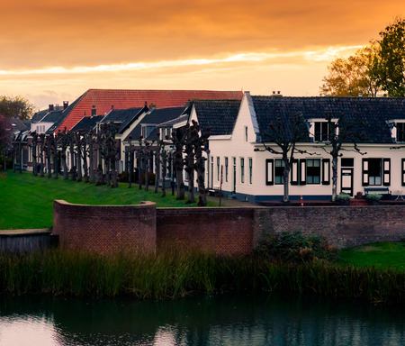 view on some modern houses with water and grass at sunset in the city Leerdam the Netherlands, typical dutch neighborhood.の写真素材