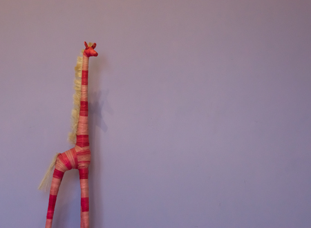 hand crafted giraffe decoration isolated on a purple wall backgroundの写真素材