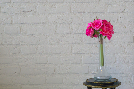 Pink roses in a glass vase isolated on a white brick wall, valentines day or interior backgroundの写真素材
