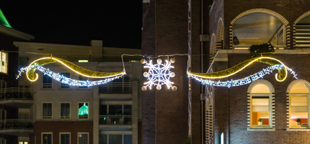 Beautiful christmas decoration with lights hanging between some buildings in the city streets at night timeの写真素材