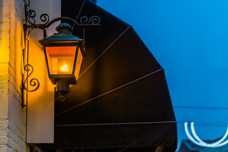 lighted vintage lantern shining light in the dark, fold canopy in the background, city architecture and lightingの写真素材