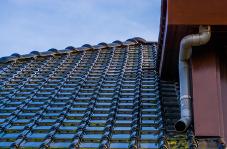 rooftop with black glossy roof tiling and a drainpipe, modern dutch architecture backgroundの写真素材