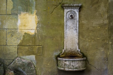old vintage drinking water fountain hanging on a stone wall, historical looking objectsの写真素材