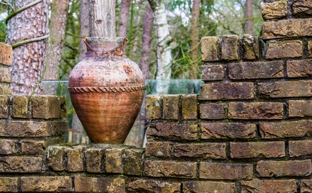 old chipped roman vase on a brick wall, outdoor garden decorations and architectureの写真素材