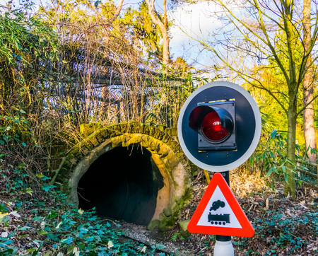 closeup of a warning traffic light, railroad tunnel with warning sign