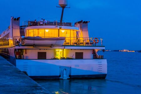 Cruise ship docked in the harbor of antwerp city, lighted boat by night, quay of antwerpen, Belgiumの写真素材
