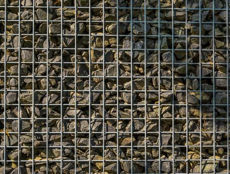 filled mesh basket with small rocks, garden architecture background, pattern of pebblesの写真素材