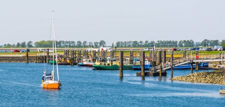 The harbor of tholen with docked ships and a boat sailing, Bergse diepsluis, Oosterschelde, zeeland, The netherlands, 22 april, 2019のeditorial素材