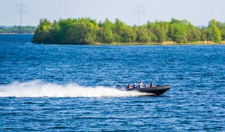 speedboat with poeple sailing by on the oosterschelde of Tholen, Touristic water sport and transportation, popular city in zeeland, The Netherlandsの写真素材