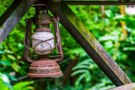 closeup of a old rusty vintage lantern with the jungle in the backgroundの写真素材