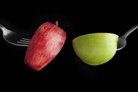 Fuji and granny smith apple slices on forks with black background.の写真素材