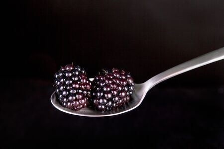 Fres blackberries on spoon with black background.の写真素材