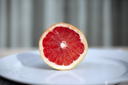 Half a grapefruit on white plate.の写真素材