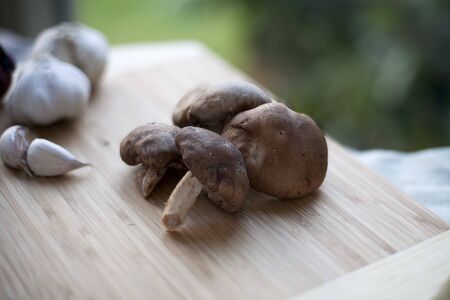Raw shitake mushrooms on cutting board.