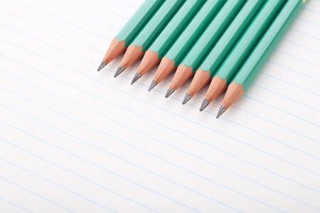 Eight green pencils on notebook paper.