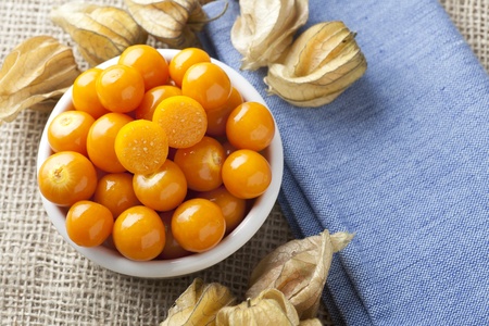 Physalis fruit with one cut in half in bowl on blue napkin and burlap.の写真素材