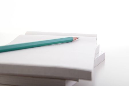 Green pencil on empty notebook with white background