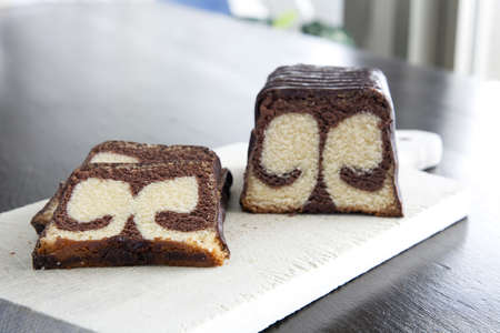 Two slices  and half a loaf of marble cake on a cutting board.の写真素材