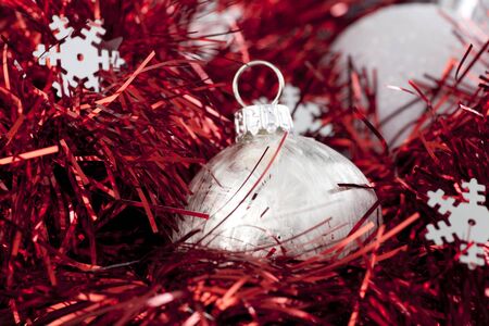 Silver christmas ball ornament sitting in red garland with silver snowflake shapes.の写真素材