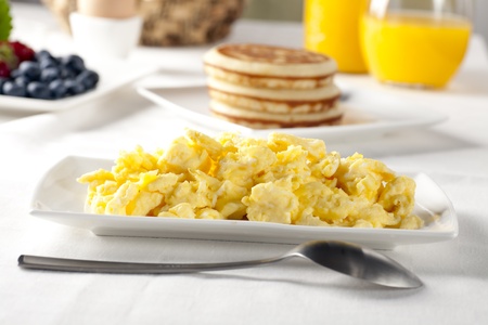 Fresh scrambled eggs and serving spoon on brunch table.の写真素材