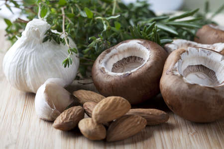Garlic, almonds, rosemary and mushroom caps, ingredients for stuffed mushrooms.の写真素材