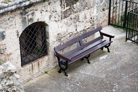 Lonely bench next to window with metal grateの写真素材